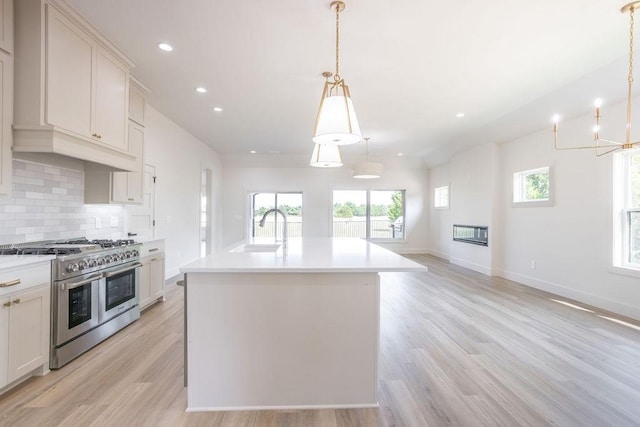 115 Palisades Dr, Gordonville, TX 76245 - kitchen with sink, double oven range, an island with sink, pendant lighting, and backsplash