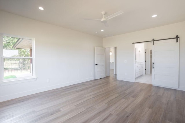 115 Palisades Dr, Gordonville, TX 76245 - unfurnished bedroom featuring ceiling fan, a barn door, connected bathroom, and light wood-type flooring