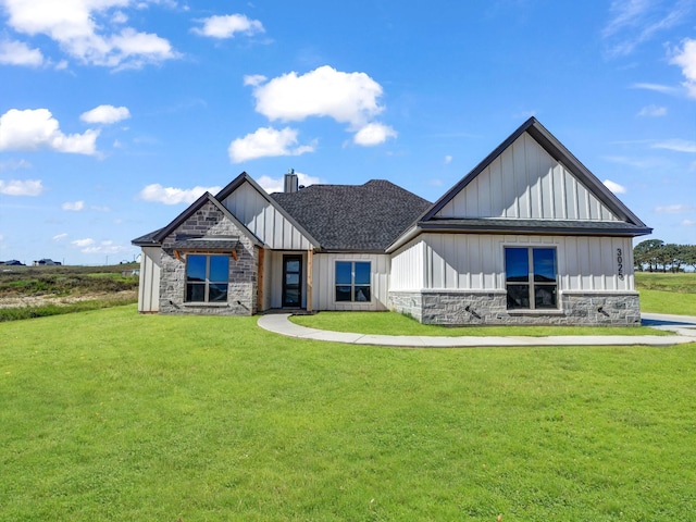 modern farmhouse with stone siding, board and batten siding, a shingled roof, and a front lawn