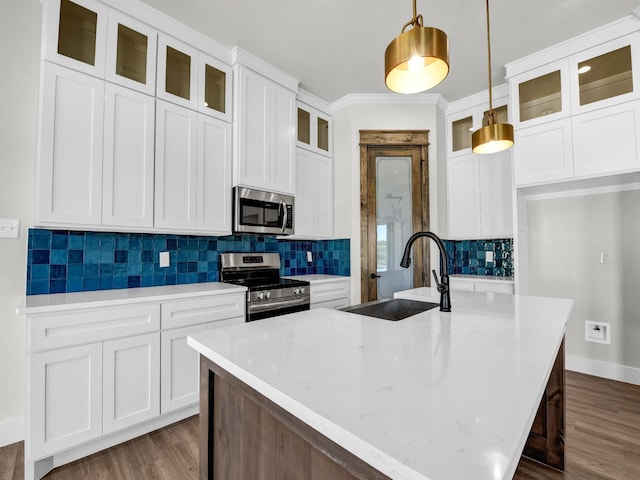 kitchen with dark wood finished floors, a center island with sink, appliances with stainless steel finishes, and a sink