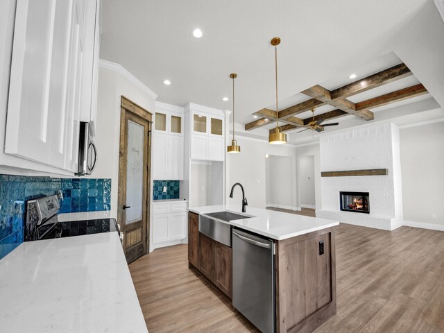 kitchen featuring light wood-type flooring, a sink, tasteful backsplash, coffered ceiling, and stainless steel appliances