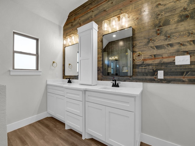 full bathroom featuring a sink, baseboards, lofted ceiling, and wood finished floors