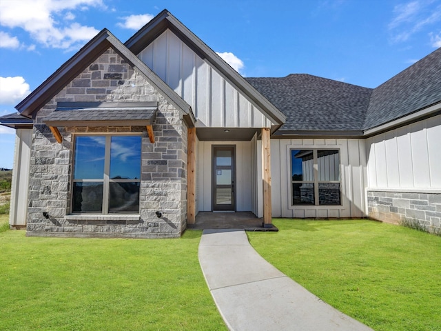 property entrance featuring a yard, stone siding, board and batten siding, and a shingled roof