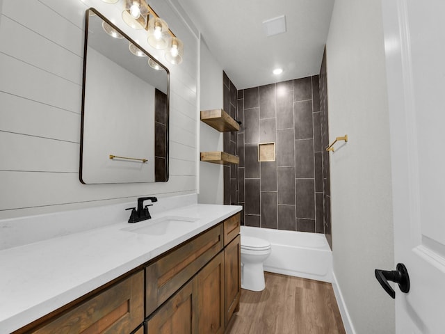 bathroom featuring toilet, shower / washtub combination, wood finished floors, baseboards, and vanity