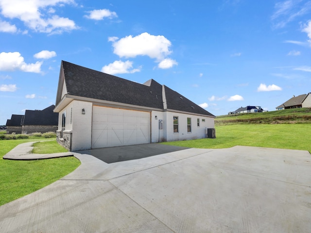 view of side of home featuring central air condition unit, a yard, concrete driveway, an attached garage, and brick siding