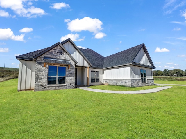 view of front of house with stone siding, board and batten siding, a front lawn, and roof with shingles