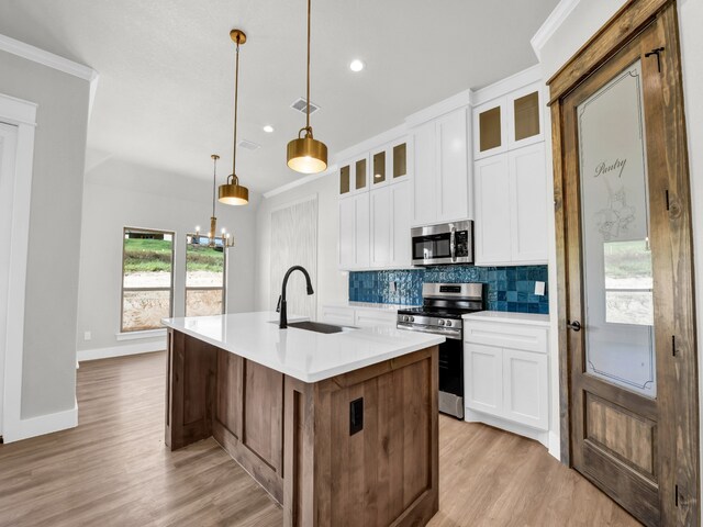 kitchen with visible vents, a sink, decorative backsplash, appliances with stainless steel finishes, and crown molding