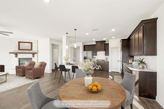 dining space with ceiling fan, a stone fireplace, and sink