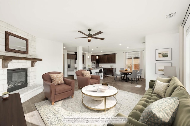 living room with a fireplace, wood-type flooring, and ceiling fan