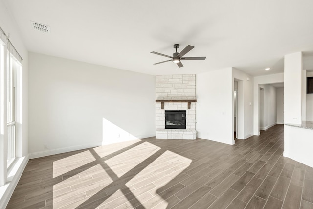 unfurnished living room with ceiling fan and a stone fireplace