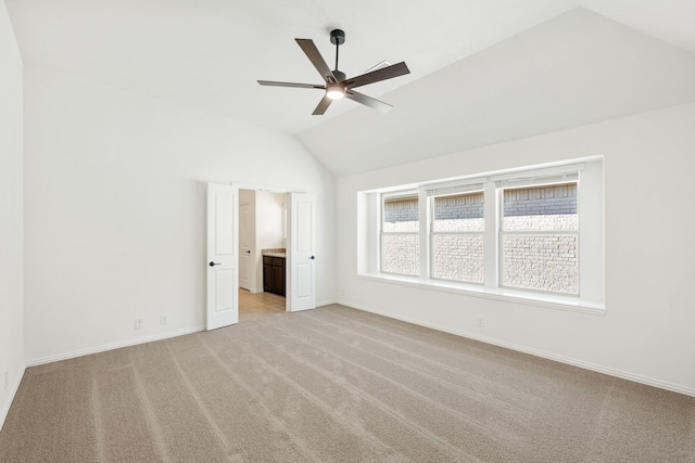 unfurnished bedroom with ceiling fan, ensuite bathroom, light colored carpet, and vaulted ceiling