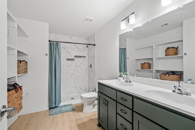 bathroom with toilet, hardwood / wood-style flooring, vanity, and walk in shower