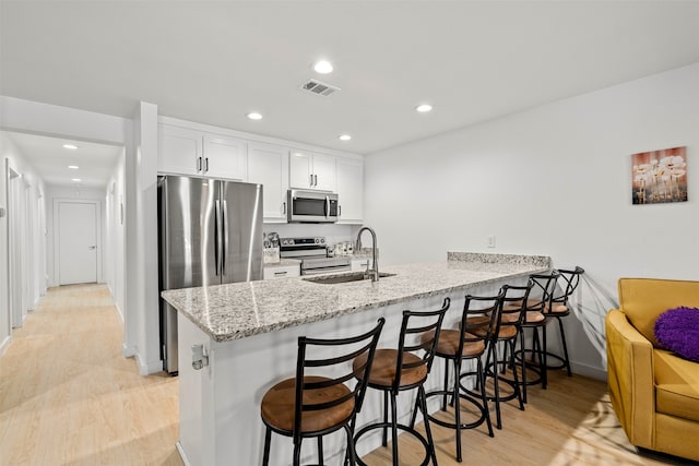 kitchen featuring light wood-type flooring, white cabinetry, sink, kitchen peninsula, and stainless steel appliances