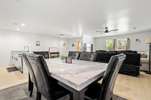 dining space featuring ceiling fan, light wood-type flooring, and sink