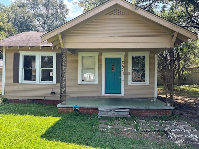 bungalow featuring covered porch and a front lawn