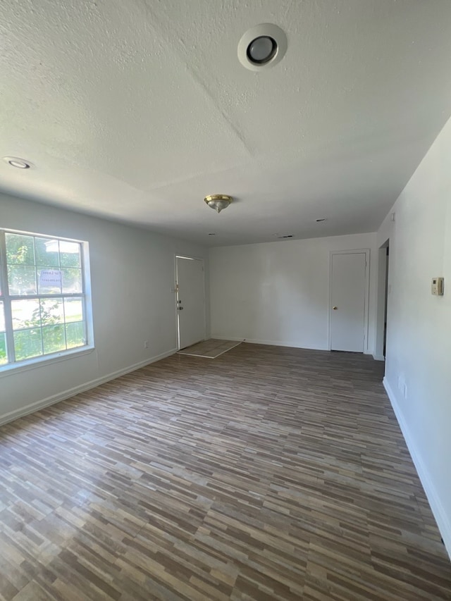 unfurnished room featuring a textured ceiling and dark hardwood / wood-style flooring