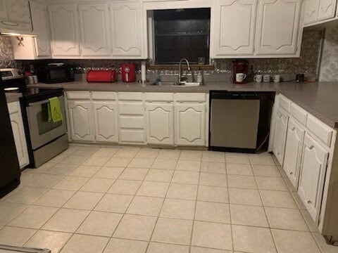 kitchen featuring appliances with stainless steel finishes, decorative backsplash, sink, white cabinets, and light tile patterned floors