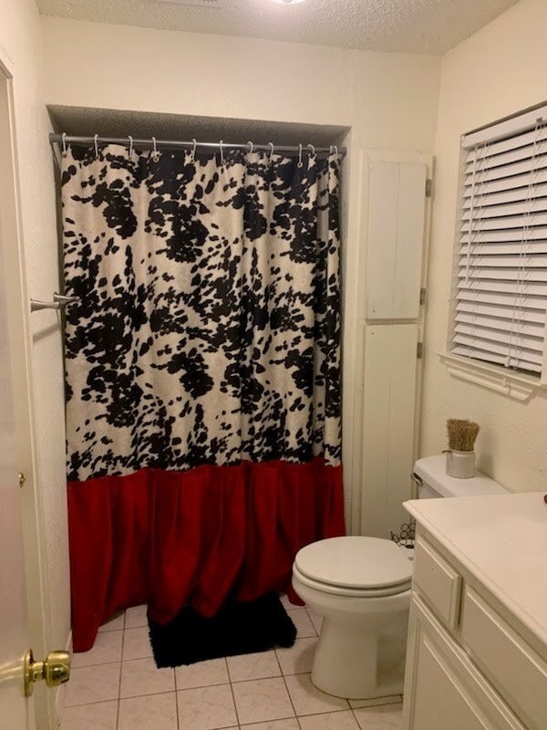 bathroom with toilet, vanity, tile patterned floors, curtained shower, and a textured ceiling