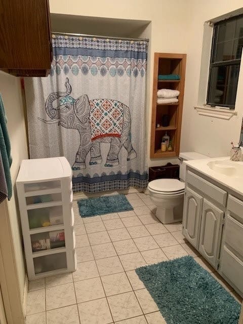 bathroom with toilet, vanity, walk in shower, and tile patterned floors