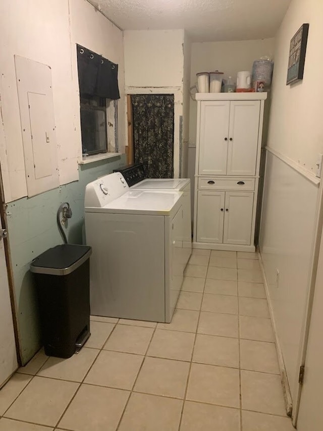 laundry room featuring independent washer and dryer, cabinets, light tile patterned flooring, and electric panel