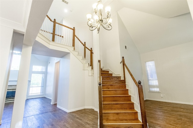 stairs featuring a chandelier, hardwood / wood-style floors, a towering ceiling, and ornamental molding