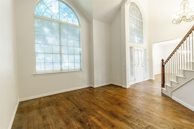 entrance foyer featuring hardwood / wood-style floors, an inviting chandelier, and high vaulted ceiling