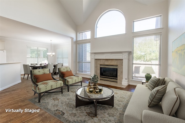 living room with a tile fireplace, hardwood / wood-style floors, a towering ceiling, and a notable chandelier