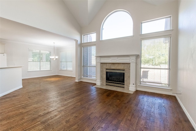 unfurnished living room featuring dark hardwood / wood-style flooring, a fireplace, high vaulted ceiling, and a chandelier