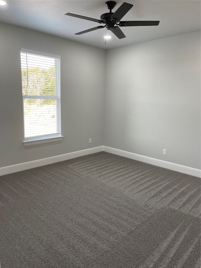 spare room featuring ceiling fan and dark carpet