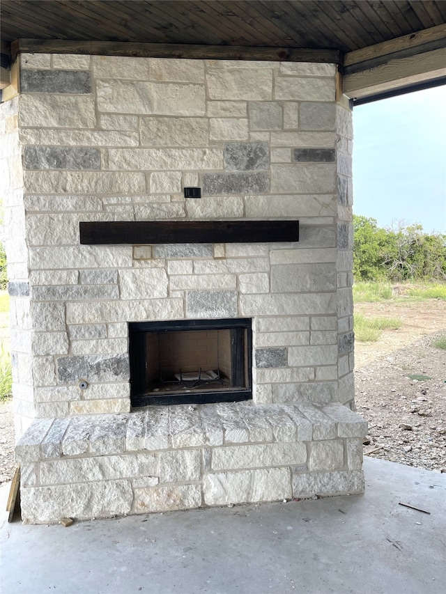 exterior details with concrete flooring, wooden ceiling, and an outdoor stone fireplace