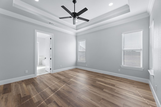 empty room featuring ornamental molding, hardwood / wood-style flooring, plenty of natural light, and a raised ceiling