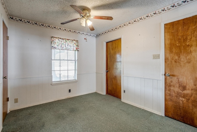 unfurnished bedroom featuring ceiling fan, dark carpet, and a textured ceiling