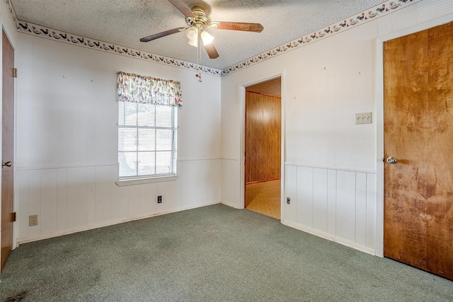 unfurnished bedroom with ceiling fan, wooden walls, carpet, and a textured ceiling