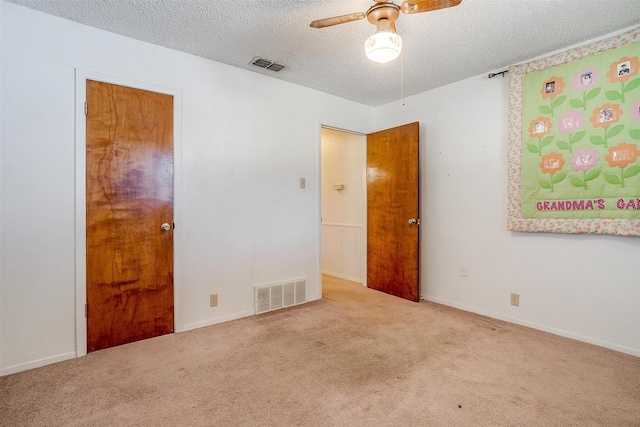 carpeted empty room featuring ceiling fan and a textured ceiling