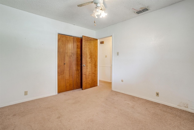 unfurnished bedroom with ceiling fan, light carpet, a closet, and a textured ceiling