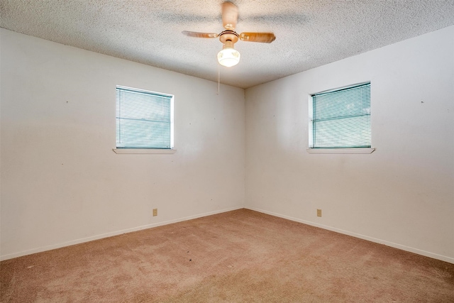 spare room featuring ceiling fan, light colored carpet, and a textured ceiling