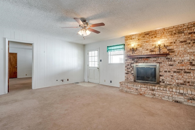 unfurnished living room with ceiling fan, carpet, a textured ceiling, and a fireplace