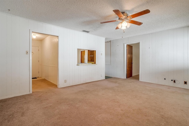 spare room featuring a textured ceiling, light colored carpet, and ceiling fan