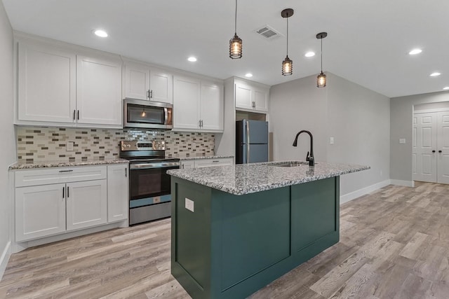 kitchen featuring appliances with stainless steel finishes, white cabinets, light wood-type flooring, and sink