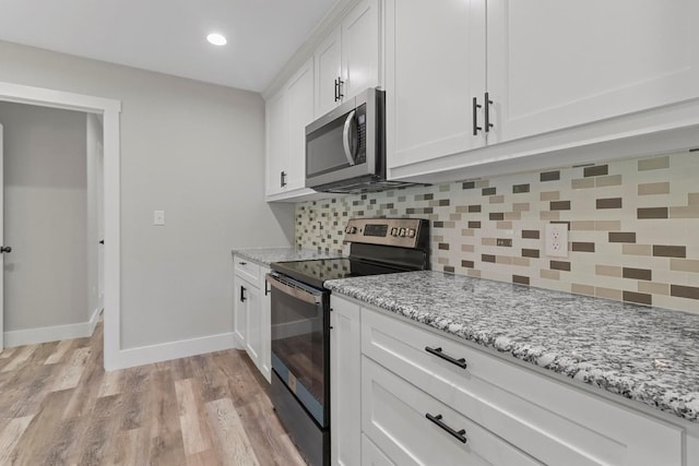 kitchen with light hardwood / wood-style flooring, decorative backsplash, range with electric cooktop, light stone countertops, and white cabinets