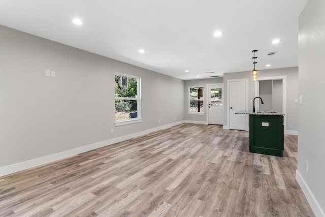 unfurnished living room featuring sink and light hardwood / wood-style floors