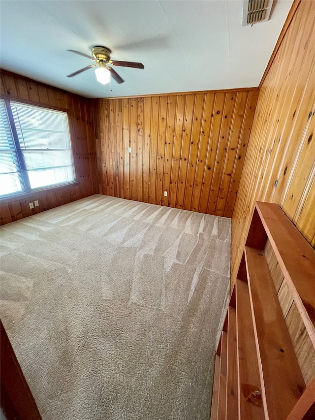 unfurnished room with ceiling fan, carpet, and wooden walls