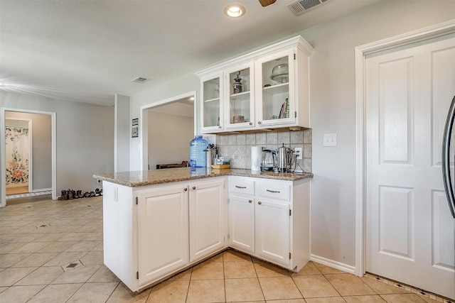 kitchen featuring light tile patterned floors, decorative backsplash, light stone counters, white cabinetry, and kitchen peninsula