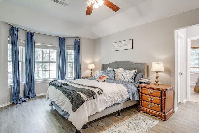 bedroom featuring multiple windows, connected bathroom, and hardwood / wood-style floors