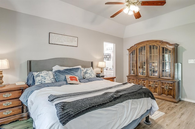 bedroom featuring light wood-type flooring, vaulted ceiling, and ceiling fan