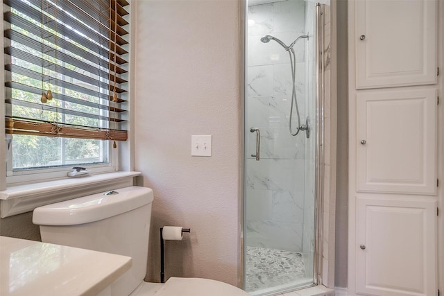 bathroom featuring a shower with shower door and toilet