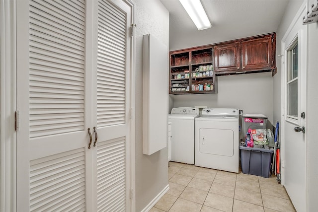 laundry room with washing machine and dryer, light tile patterned floors, and cabinets