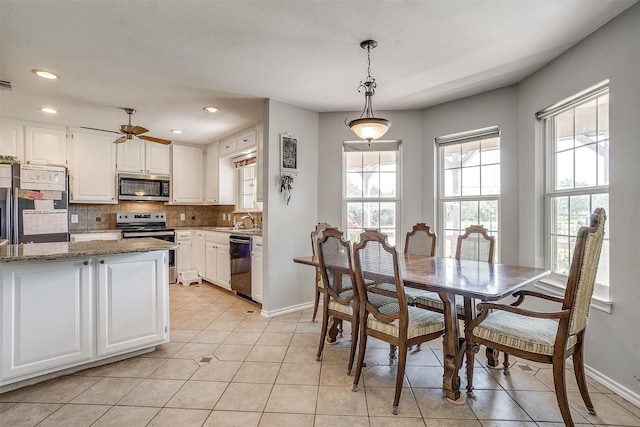 tiled dining space featuring ceiling fan and sink