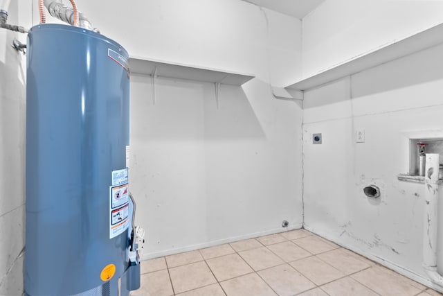 clothes washing area with hookup for an electric dryer, gas water heater, hookup for a washing machine, and light tile patterned flooring