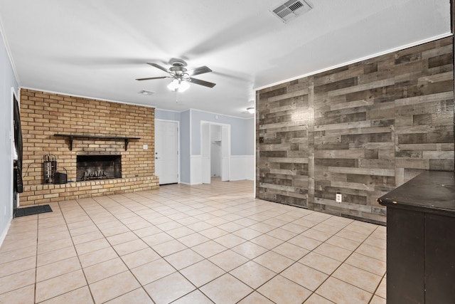 unfurnished living room featuring light tile patterned floors, ornamental molding, ceiling fan, and a brick fireplace